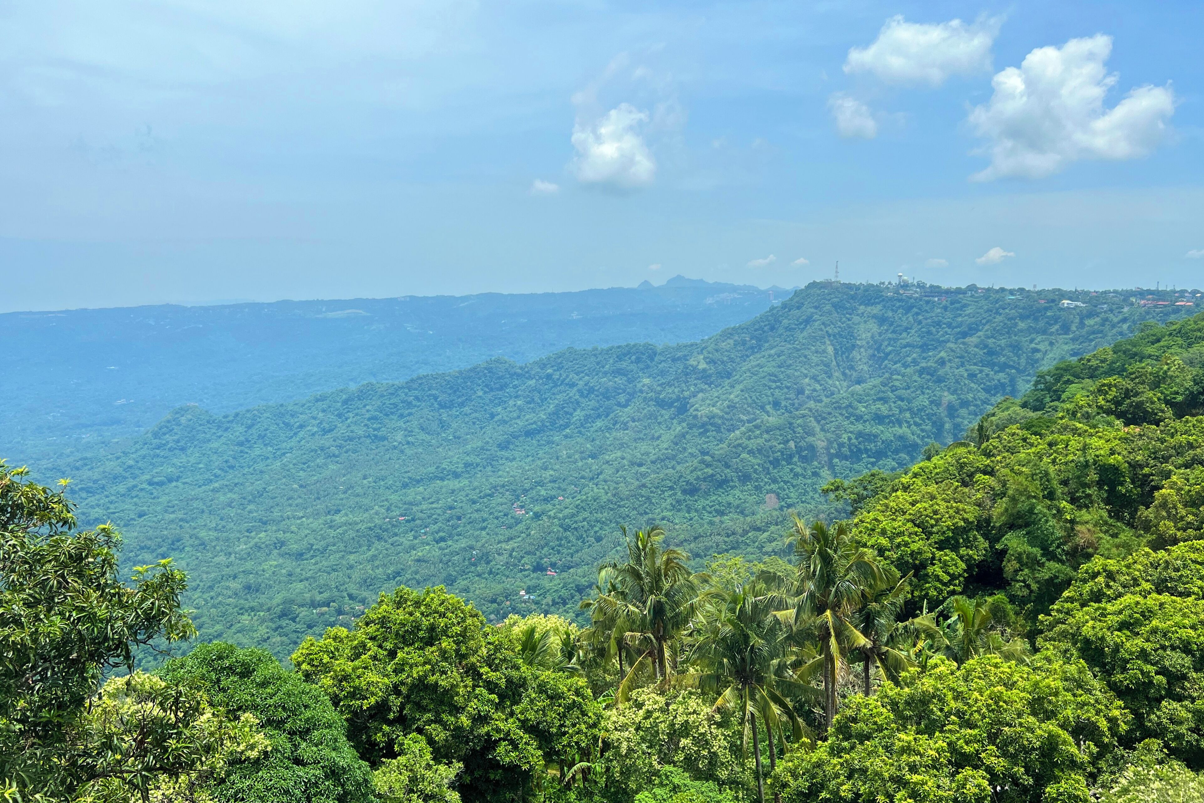 A mountainous landscape with dense green vegetation and a clear sky.