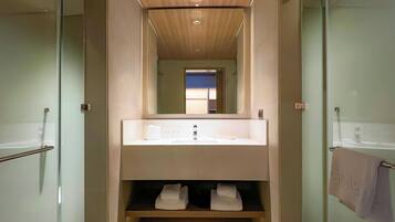 Une salle de bain moderne avec une douche à parois de verre, un grand miroir au-dessus du lavabo et un porte-serviettes fixé au mur.