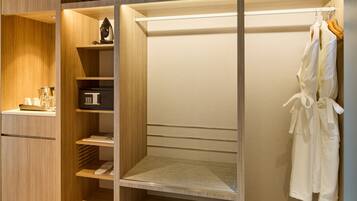 A walk-in closet with a hanging robe rack, shelves with storage items, and a shoe rack.