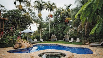 Una piscina al aire libre, sombrillas, sillones reclinables de piscina