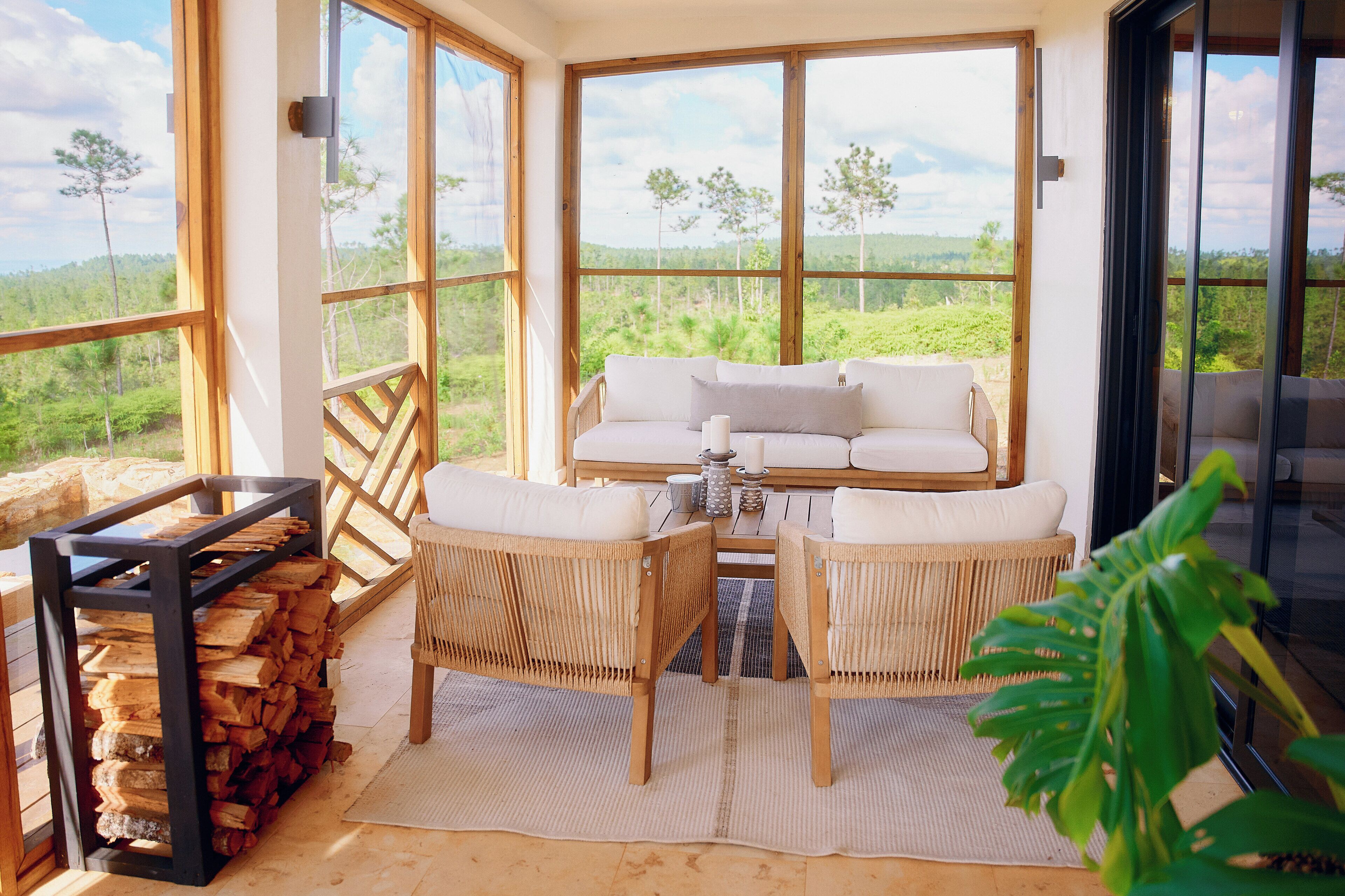 A cozy room with a sofa, two chairs, a table, and a stack of firewood.