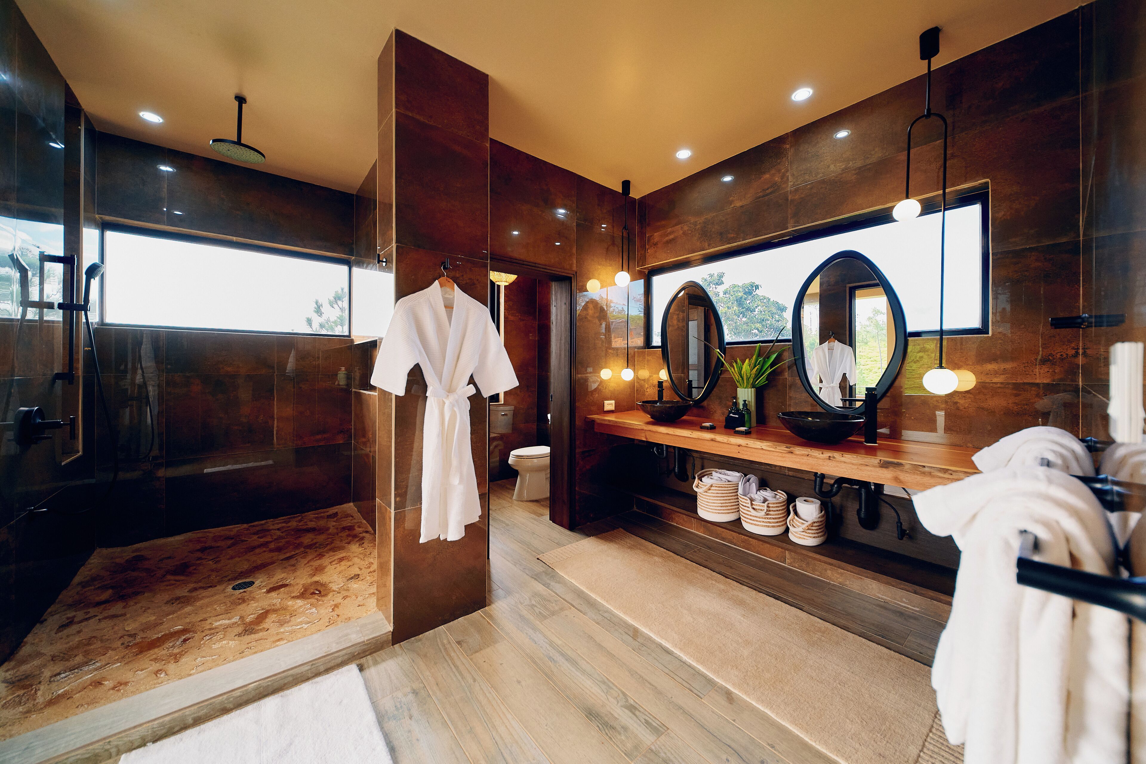 Une salle de bain moderne avec un grand miroir, un meuble-lavabo en bois et une cabine de douche en verre.