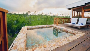 A hot tub on a wooden deck with a view of a forested area.