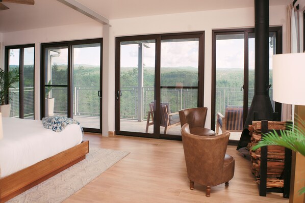 A bedroom with a large bed, a wooden floor, a sofa, and a fireplace.