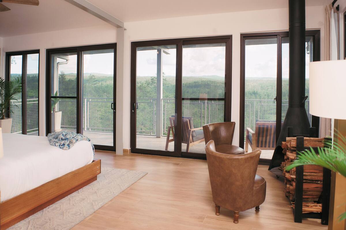 Un dormitorio con una cama grande, piso de madera, un sofá y una chimenea.