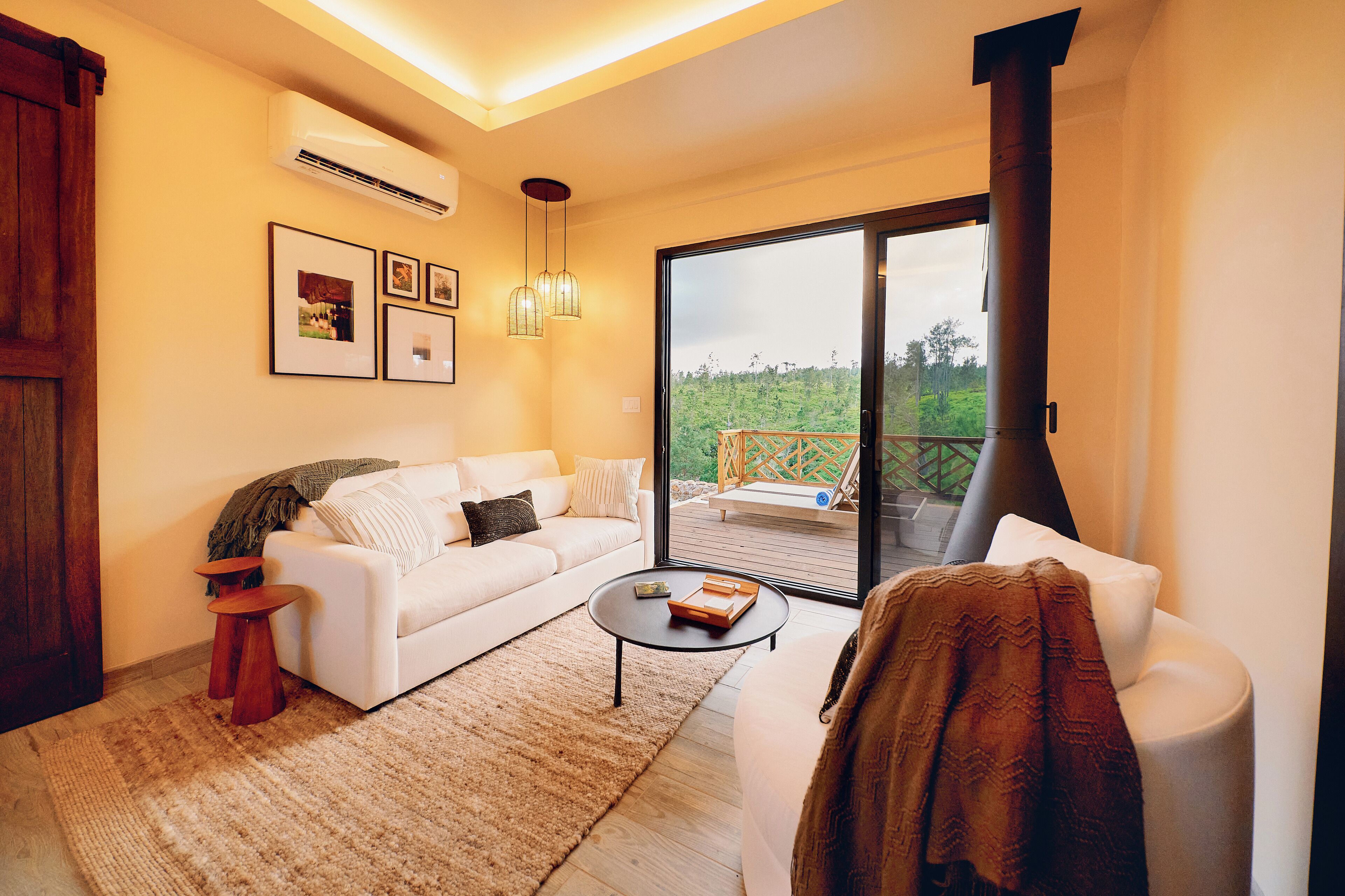 A modern living room with a white sofa, a coffee table, and a large sliding glass door leading to an outdoor deck.