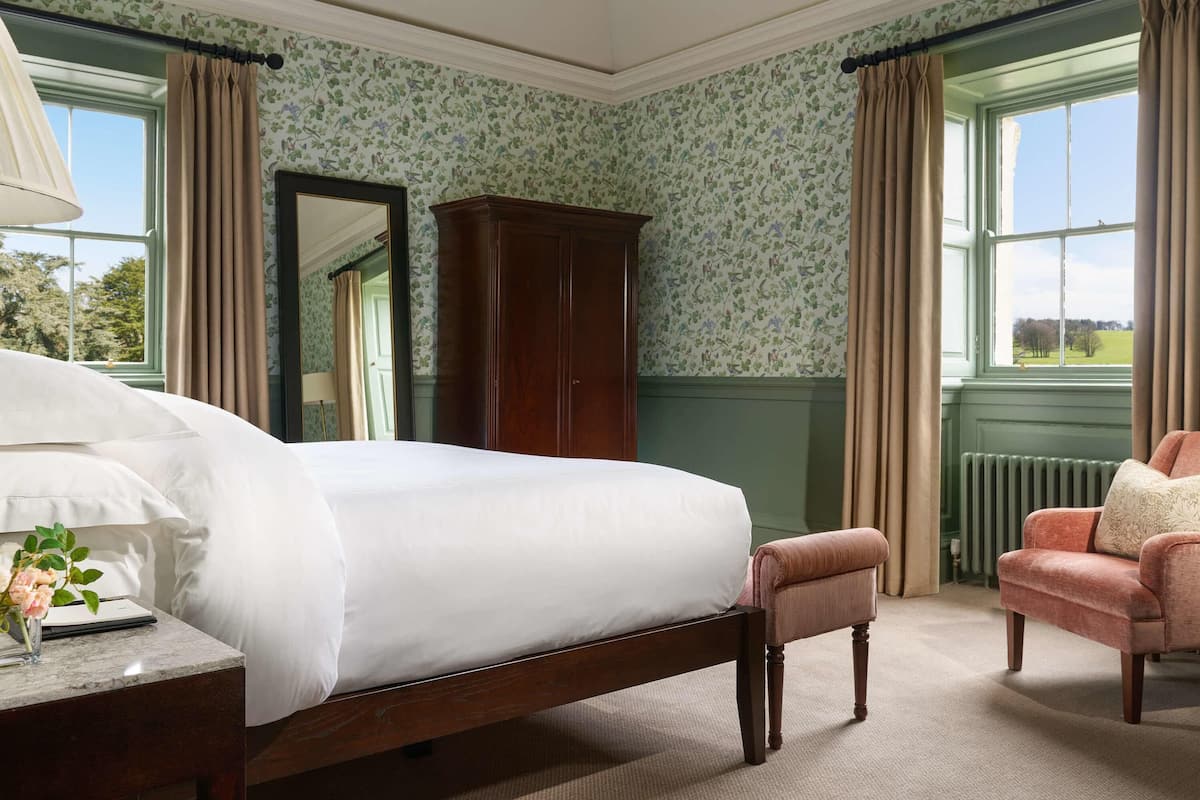 Une chambre à coucher avec un lit, une armoire en bois, une chaise et une vue sur l’extérieur.