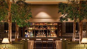 A bar area with a variety of liquor bottles, wooden chairs, and tables.