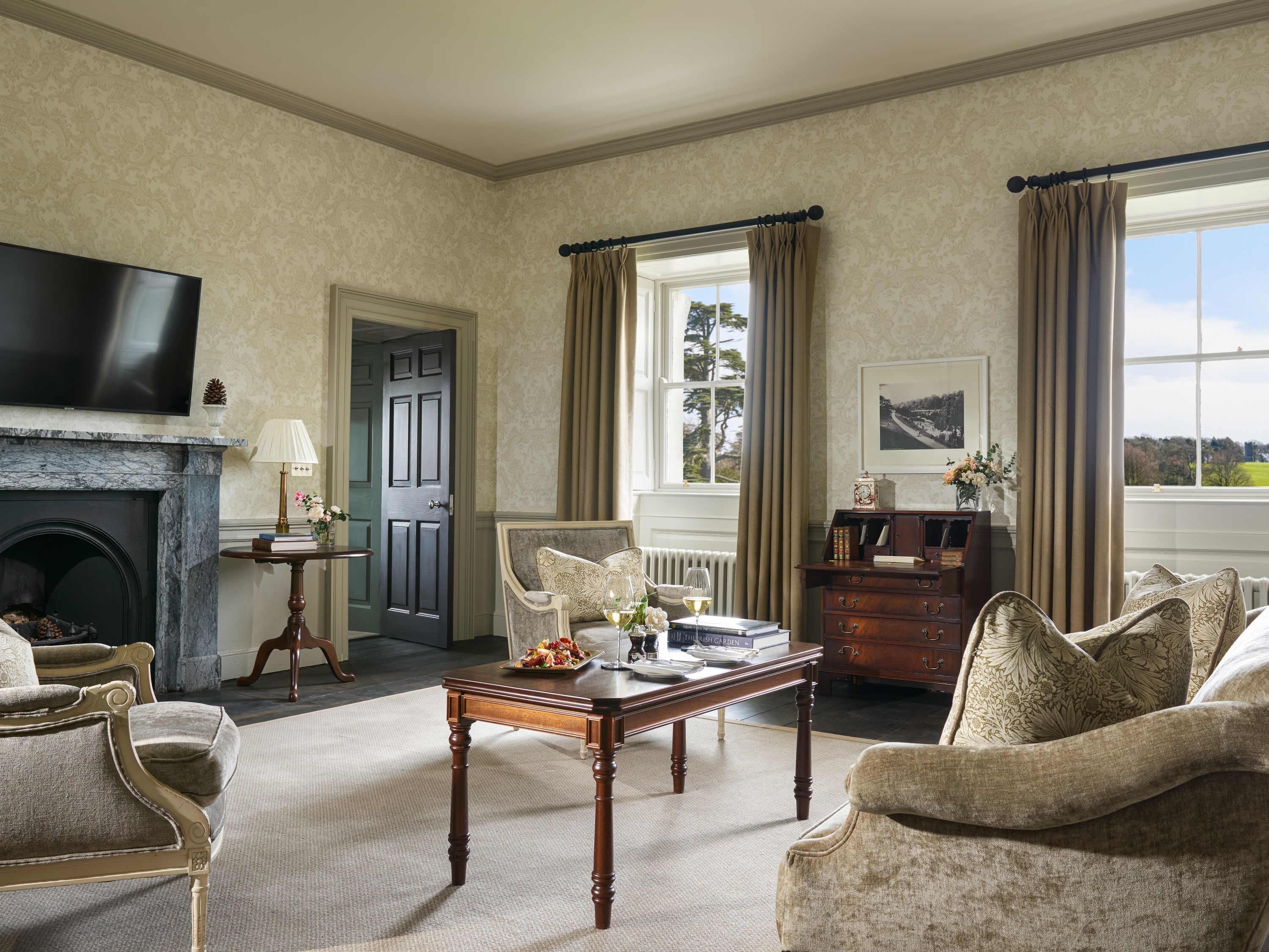 A room with a fireplace, a television, a dining table, and a view of the outdoors.
