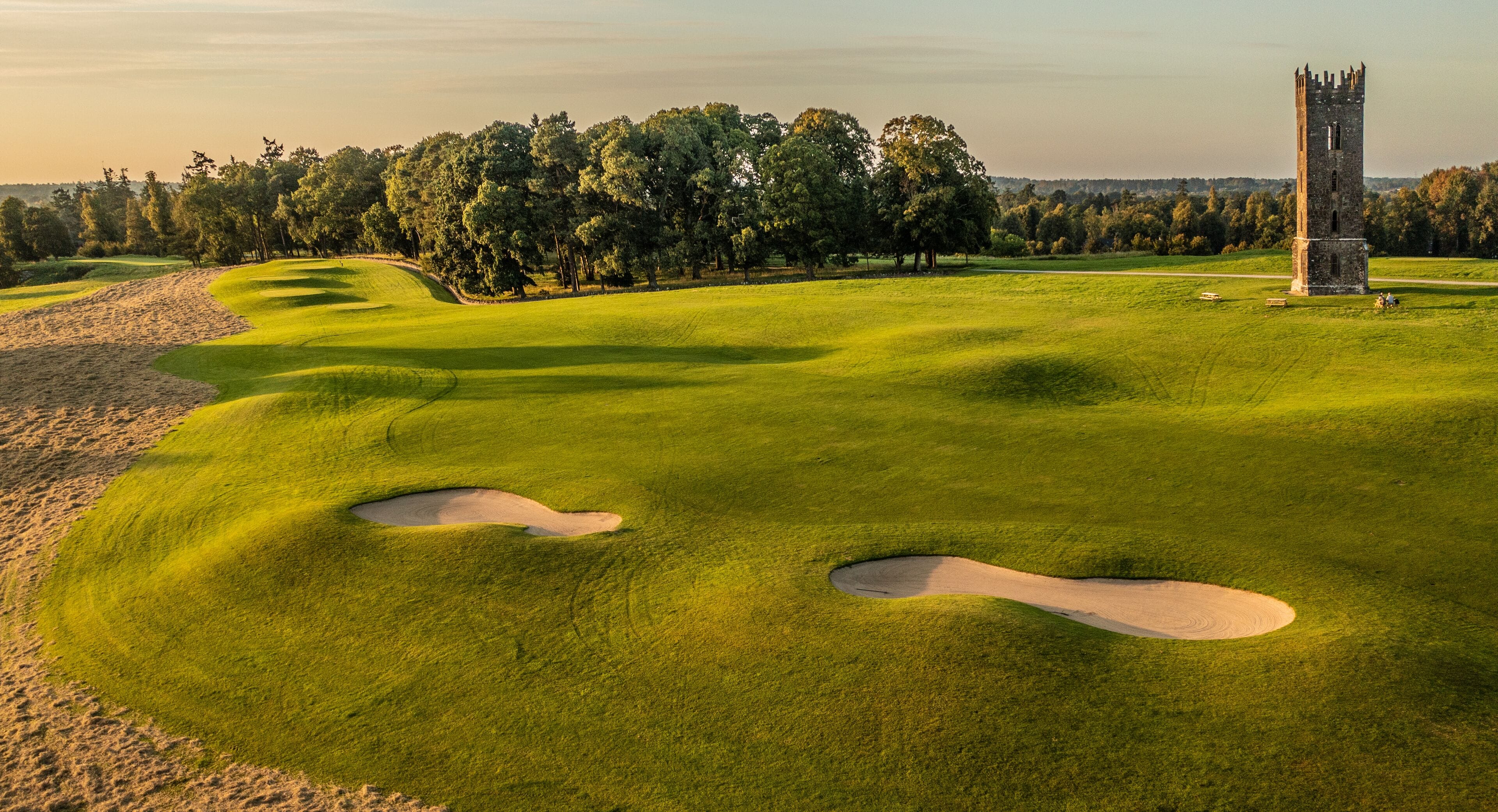 Ein Golfplatz mit Sandbunkern und einem Turm.
