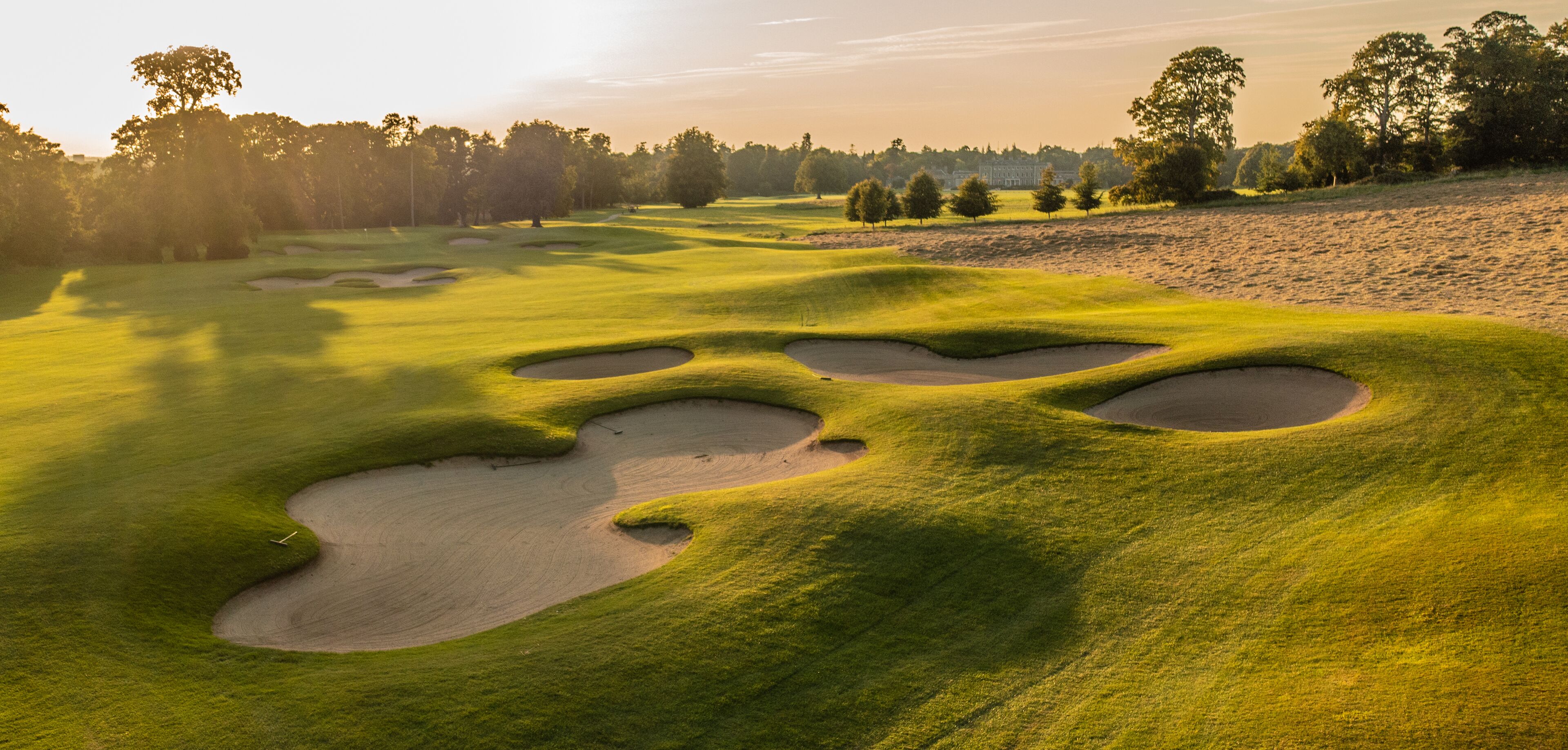 Un campo de golf con búnkeres de arena y un club de campo al fondo.