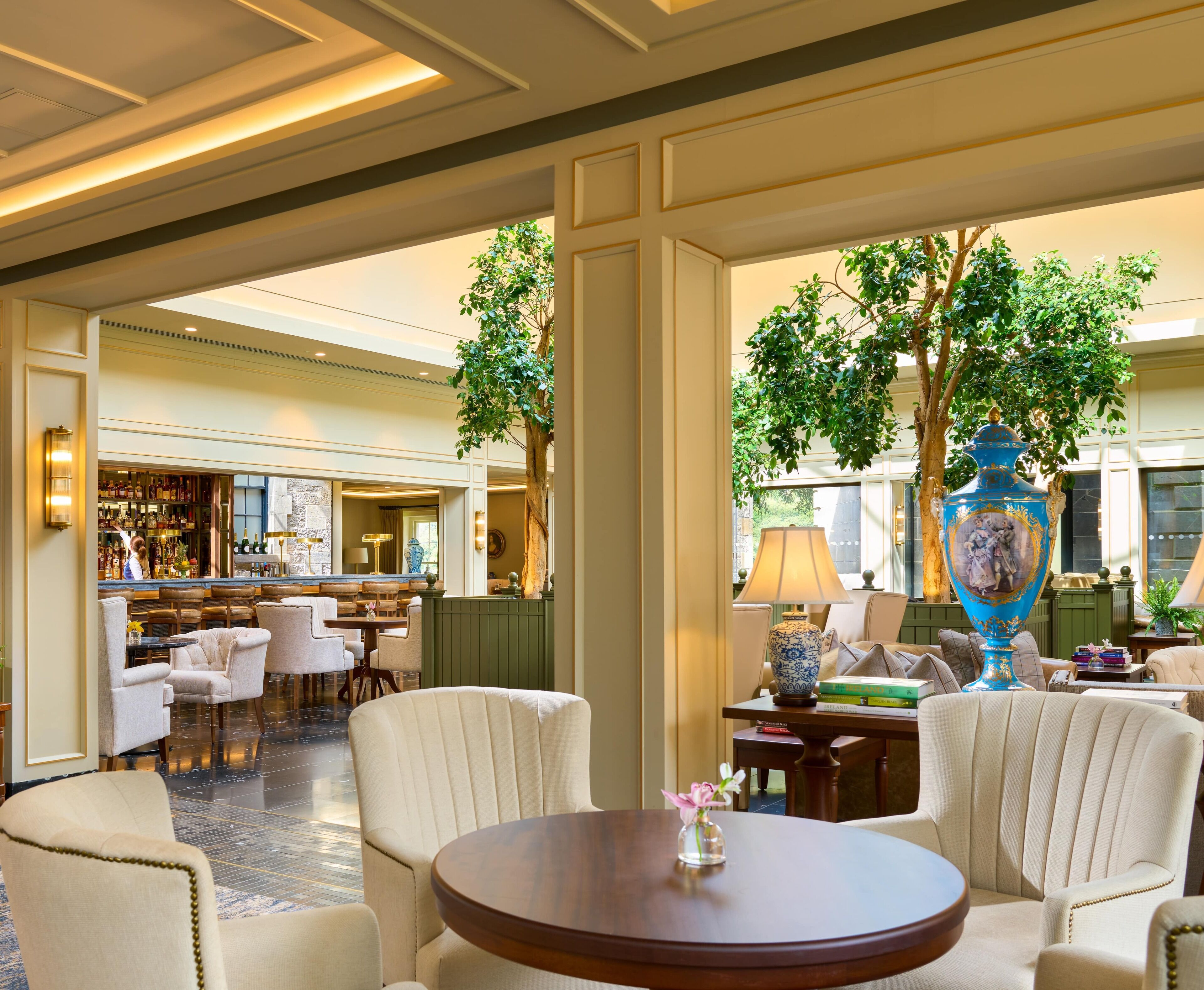 A hotel lobby with a bar, seating area, and a large vase.