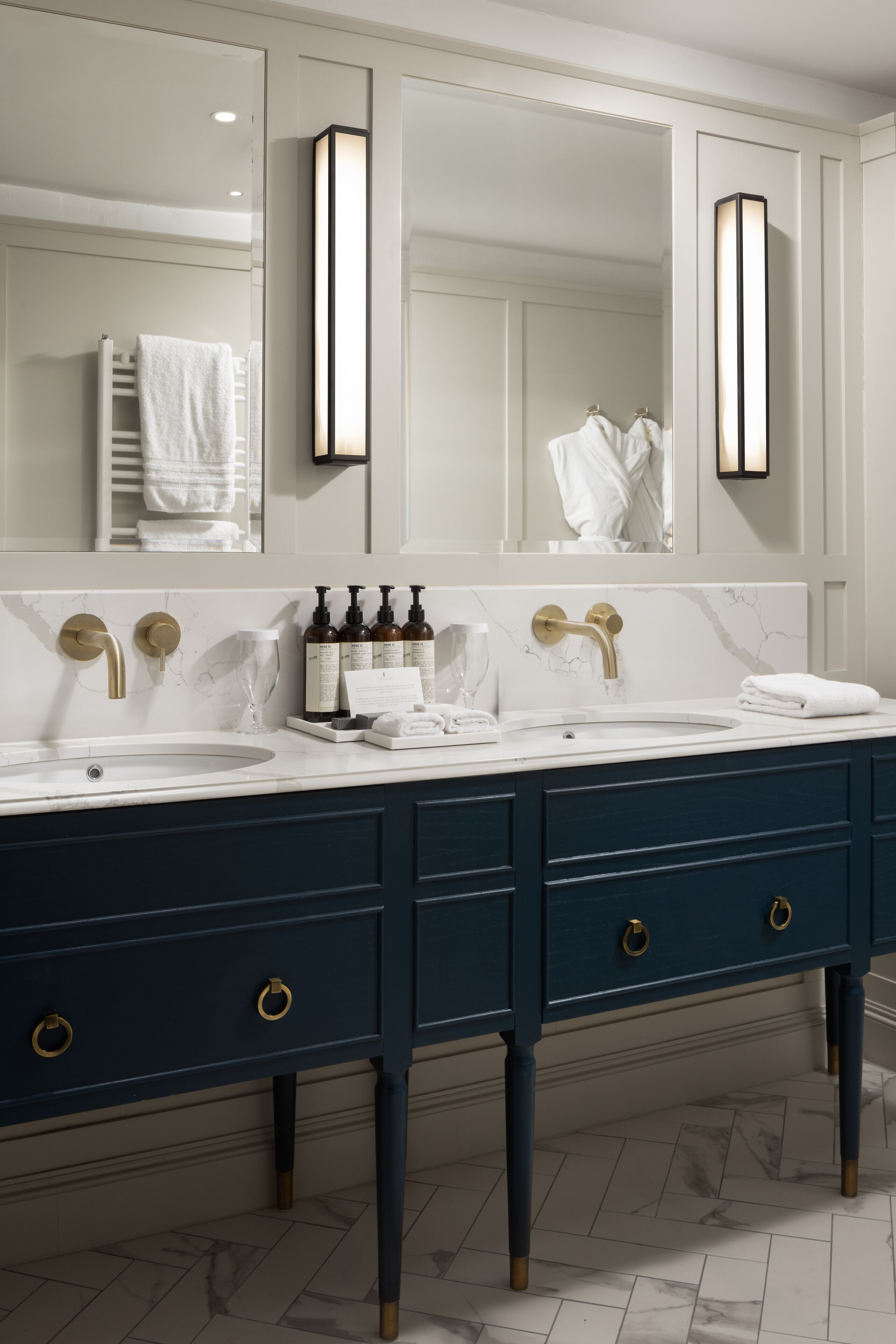A bathroom with a double sink, two mirrors, and a vanity with drawers.