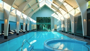 Une piscine intérieure au design moderne, dotée d’un espace central circulaire et d’une partie rectiligne avec des chaises longues.