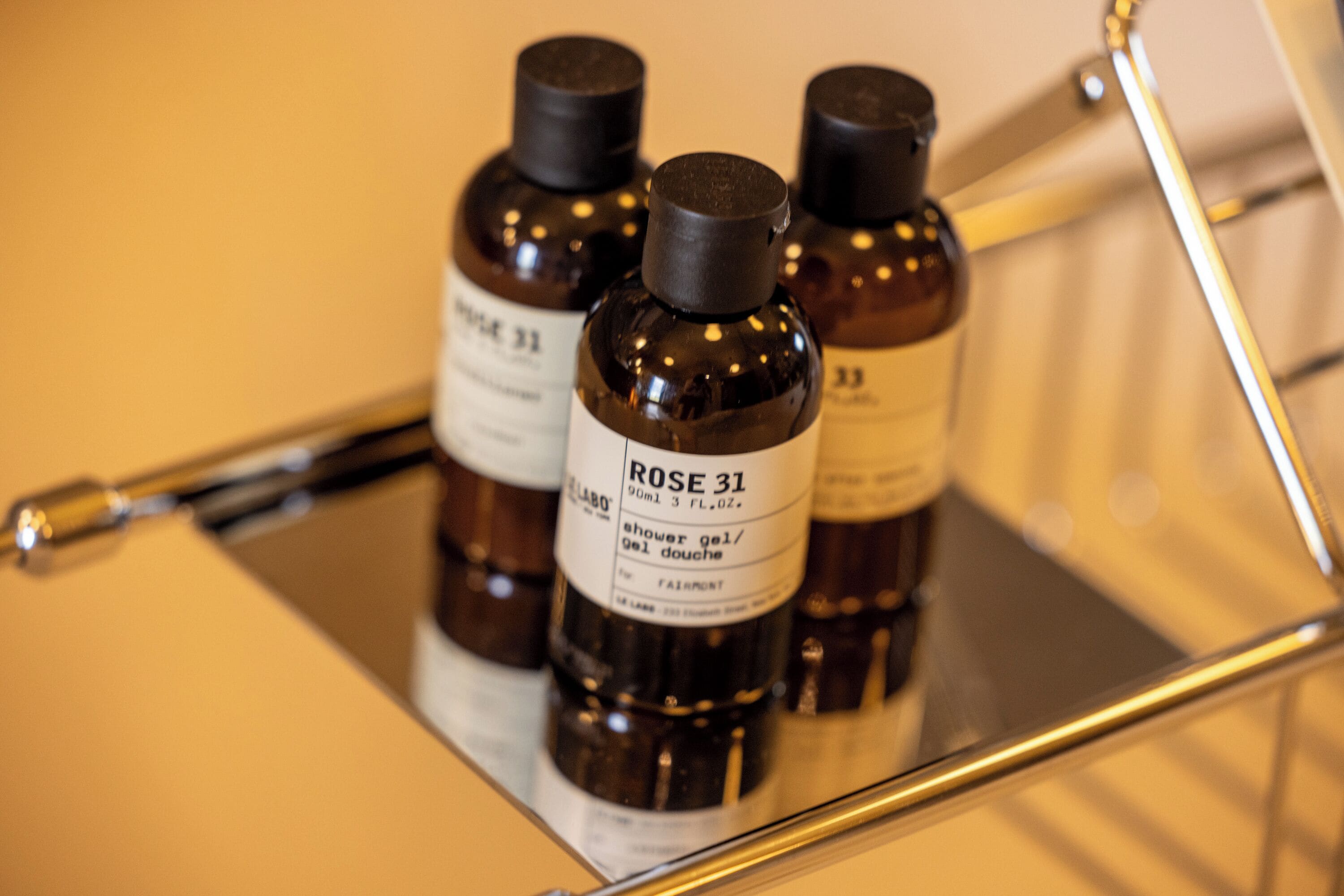 Three bottles of shower gel on a metal shelf.