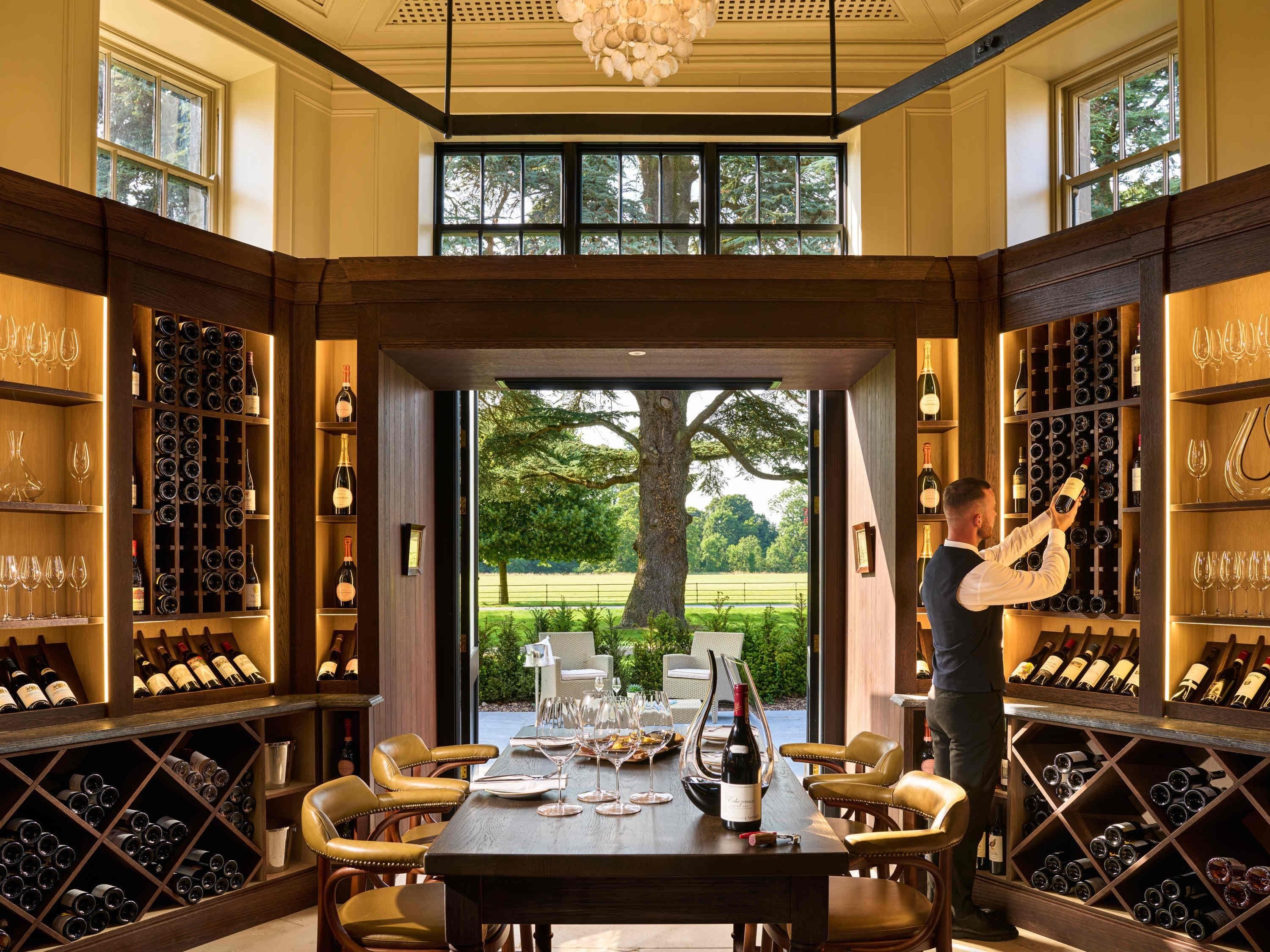 A wine cellar with a large oak table, leather chairs, and extensive wine racks.