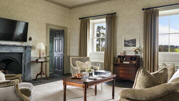 Ein Zimmer mit Kamin, Fernseher, Esstisch und Blick ins Freie.