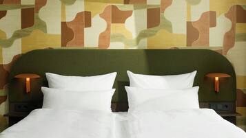 Een bed met witte beddengoed, twee wandlampen en een behang met patroon.