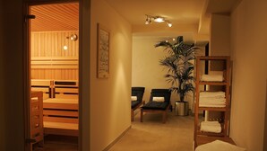 Un pasillo con sauna, zona de estar y un estante con toallas.