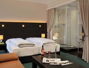 A hotel room with two beds, a shower, a table with a bottle of wine and glasses, and a vase with a flower. - Fleming's Conference Hotel Frankfurt (Frankfurt)