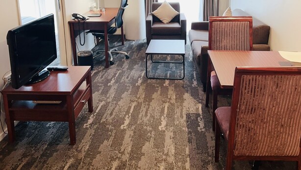 A hotel room with a TV, desk, chair, sofa, and a small table. - VR Auckland City (Auckland)