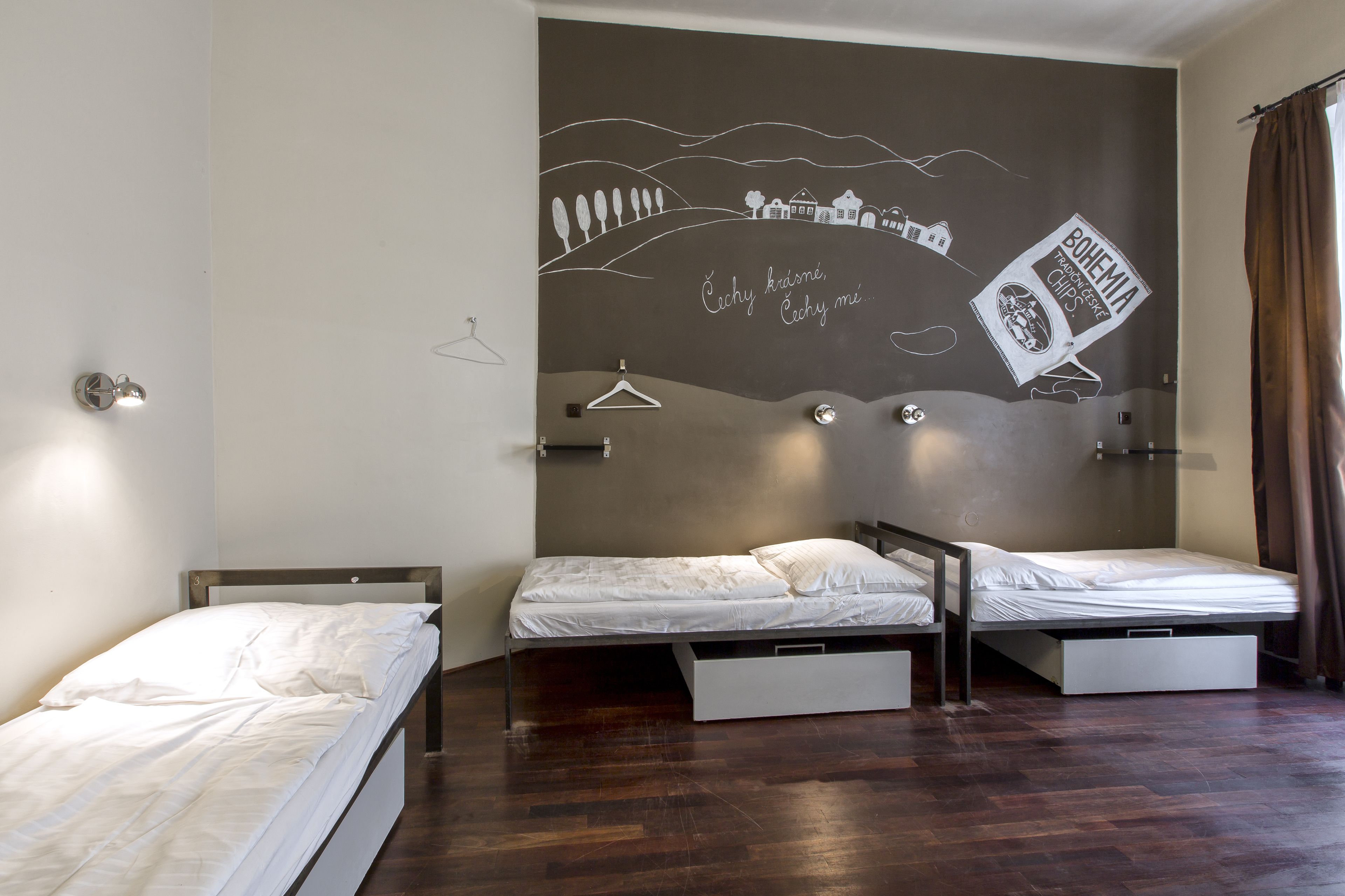 A room with two beds, a wall mural, and a wooden floor.