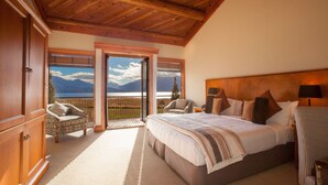 A bedroom with a large bed, a view of mountains, and a balcony. - Fiordland Lodge (Te Anau)