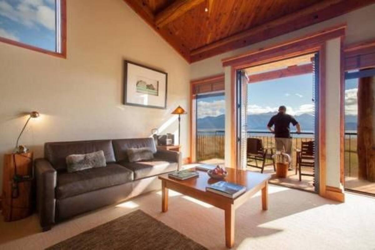 Ein Wohnzimmer mit einer Couch, einem Couchtisch und Blick auf Berge durch große Fenster.