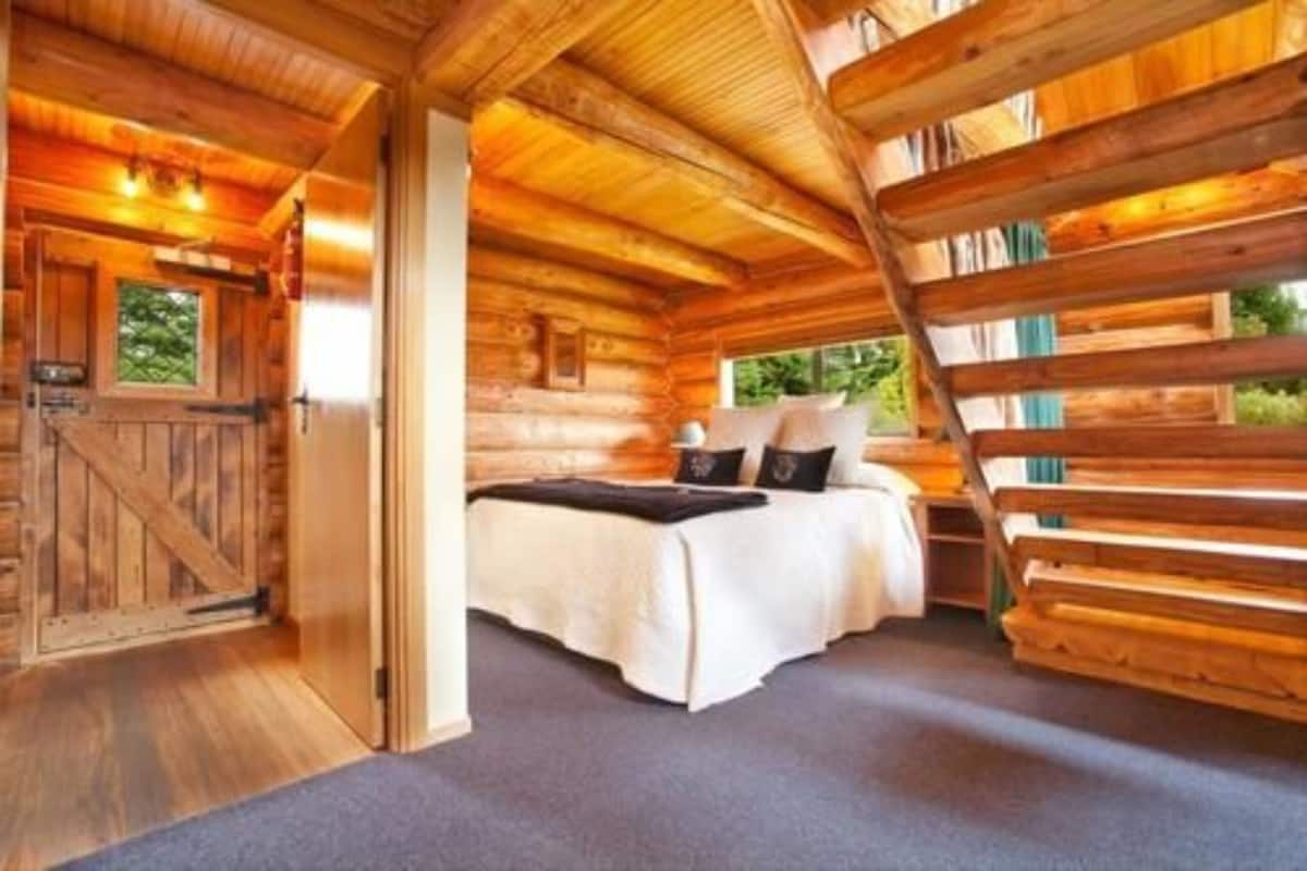 Ein Schlafzimmer in einer Blockhütte mit einem Bett, Kissen und einem Fenster.