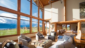 A spacious living area with large windows, a fireplace, and a view of the outdoors. - Fiordland Lodge (Te Anau)
