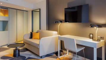 Een moderne hotelkamer met een bank, een bureau, een ronde tafel en een grote spiegel.