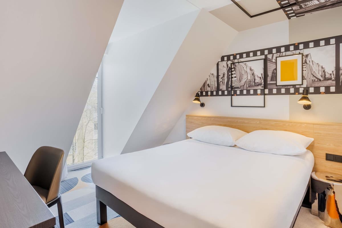 Quarto de hotel moderno com uma cama grande, uma escrivaninha e uma cadeira.