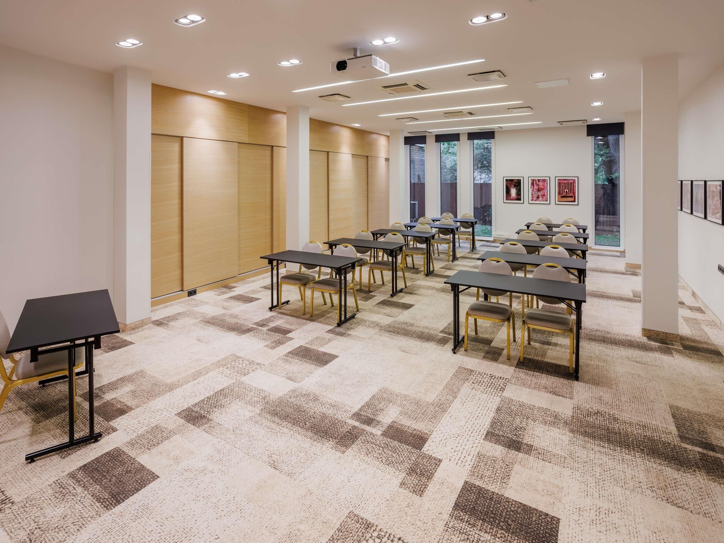 A conference room with tables and chairs, a projector, and a large window with artwork on the wall.