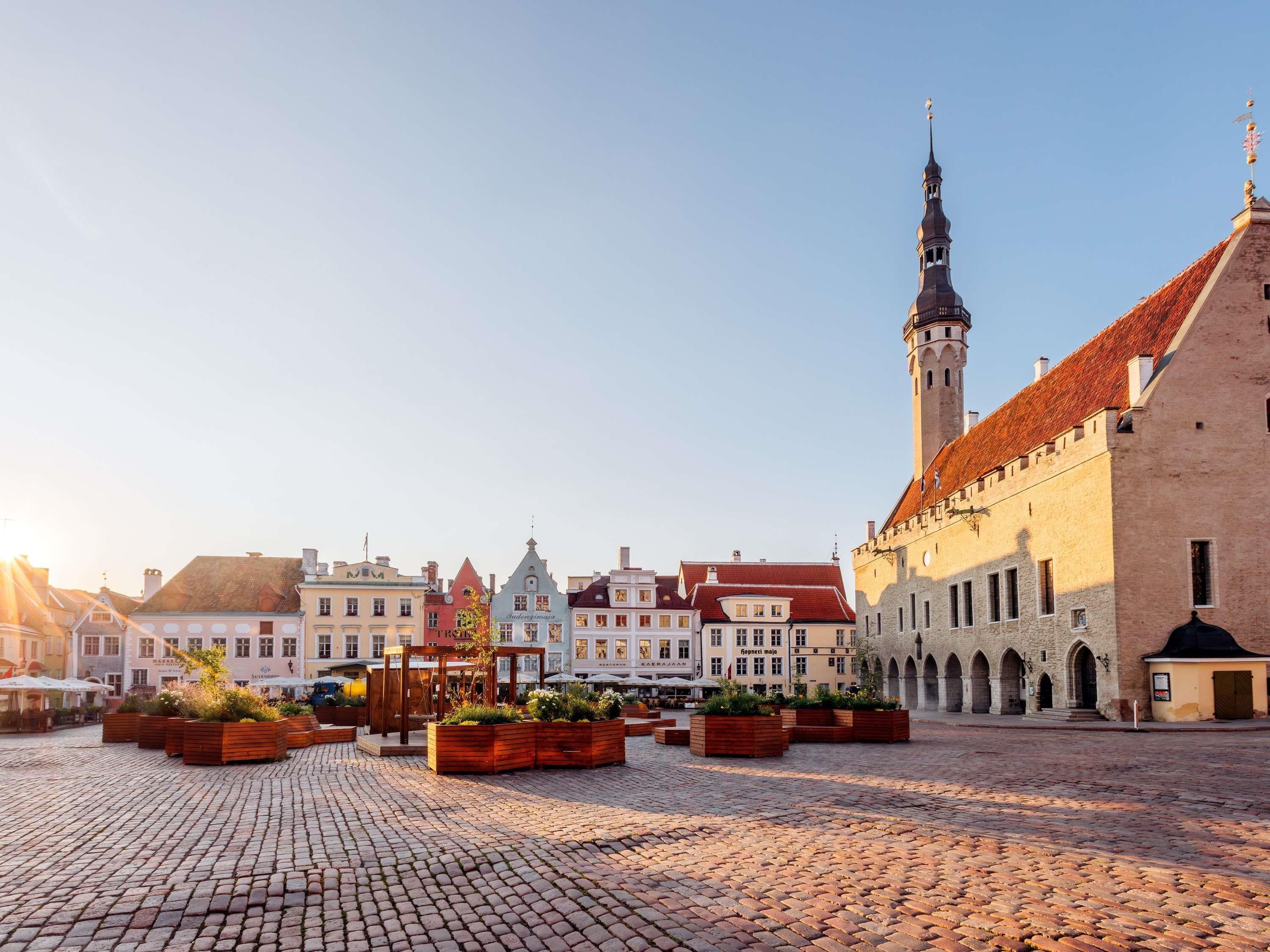 A cobblestone square with historic buildings and a prominent tower.