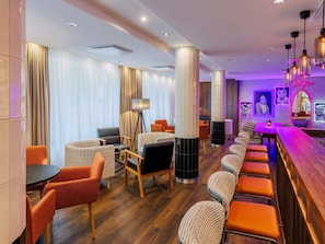 Un hall d’hôtel avec des espaces aménagés pour s’asseoir, un bar et un miroir pour prendre des selfies.