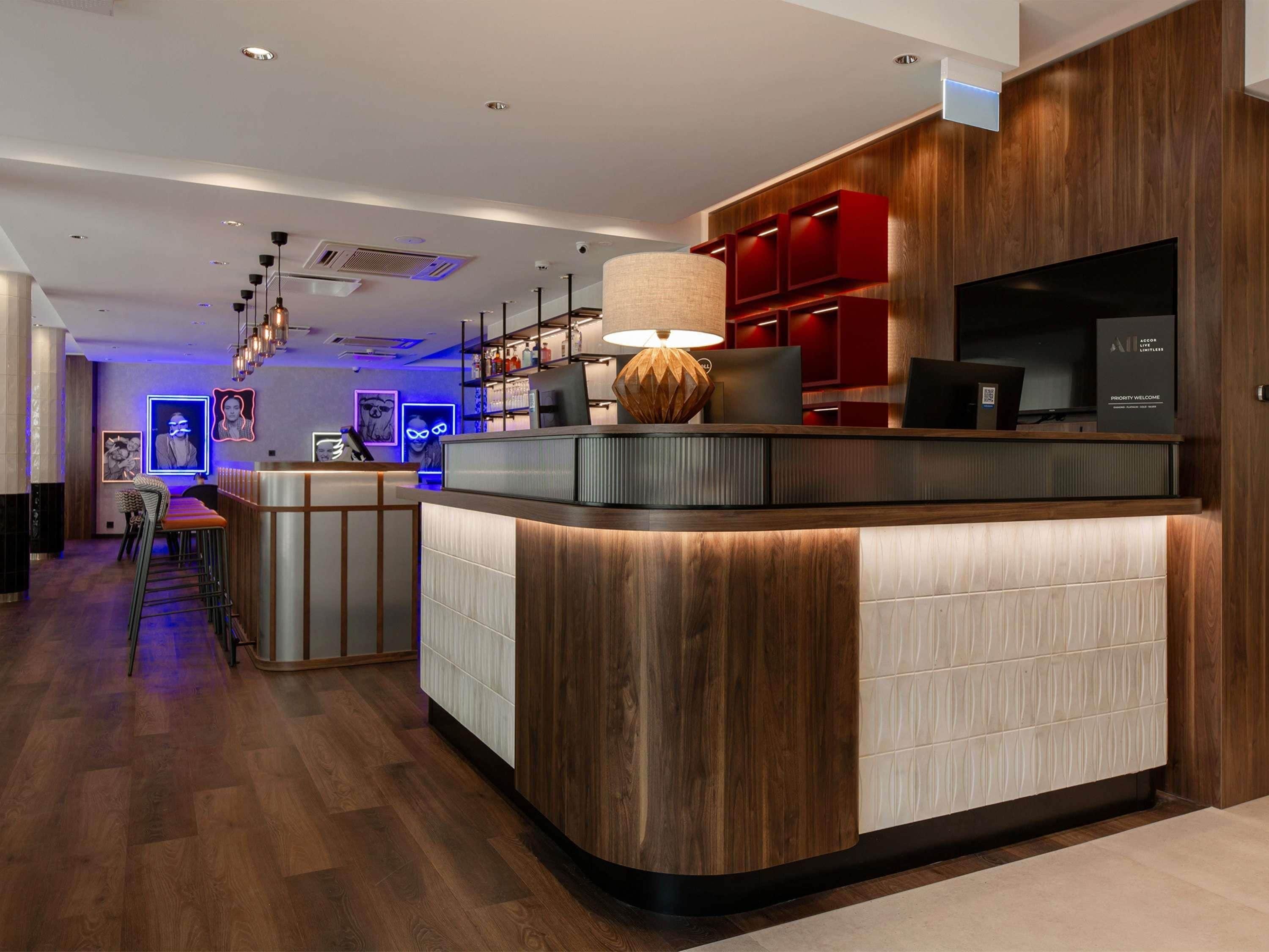 A modern reception area with a curved counter, wooden paneling, and a red accent wall.