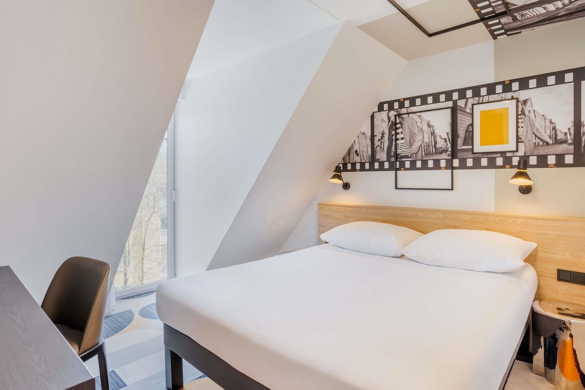 Una habitación de hotel moderna con una cama, un escritorio y una silla.