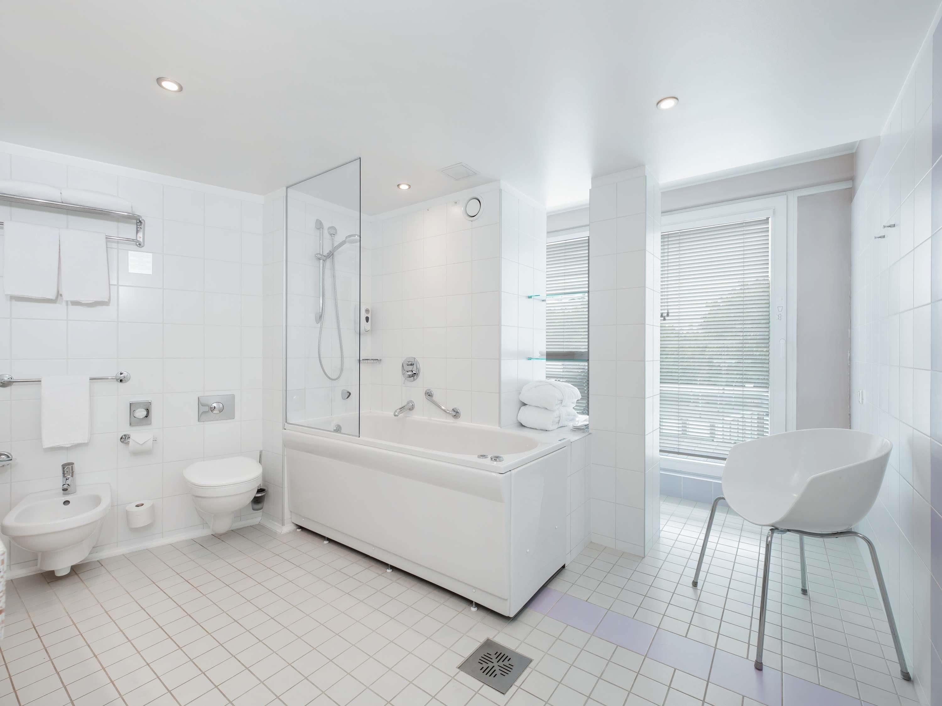 A modern bathroom with a bathtub, a shower, a toilet, and a sink.