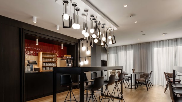 Un área de comedor moderna con barra, suelo de madera y lámparas de diseño contemporáneo.
