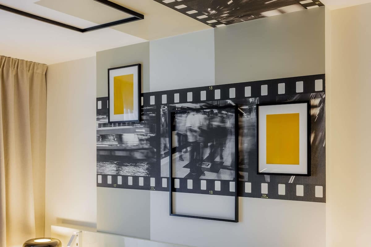 Une chambre d’hôtel avec un lit, une table de chevet avec une lampe et un mur orné de tableaux.