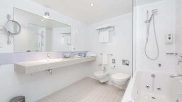 A modern bathroom with a large mirror, a sink, a toilet, a shower, and a bathtub.