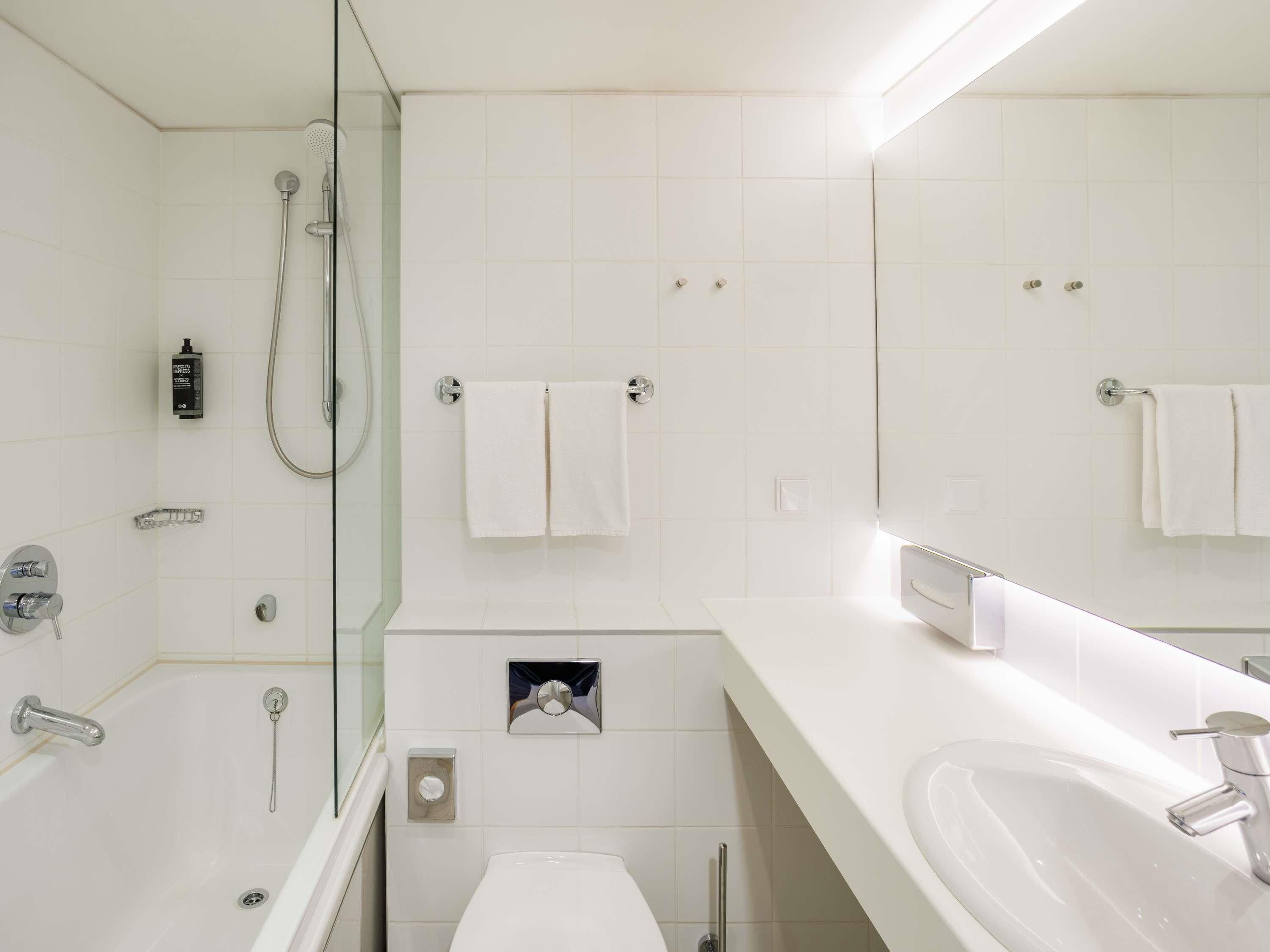 Une salle de bain moderne équipée d’une baignoire, d’une douche, de toilettes et d’un lavabo.