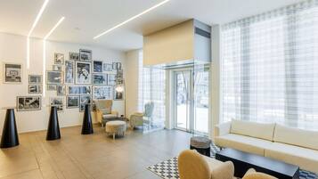 A modern living room with a sofa, chairs, a coffee table, and a wall adorned with framed pictures.