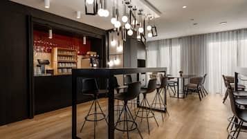 Een moderne eetruimte met een bar, houten vloeren en moderne verlichtingsarmaturen.