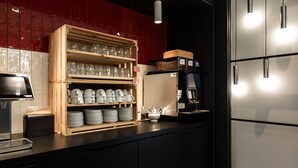 Una cocina moderna con estantes de madera que sostienen copas y platos, una cafetera y un refrigerador de acero inoxidable.