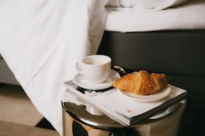 Una bandeja con un croissant y una taza de café sobre una revista.
