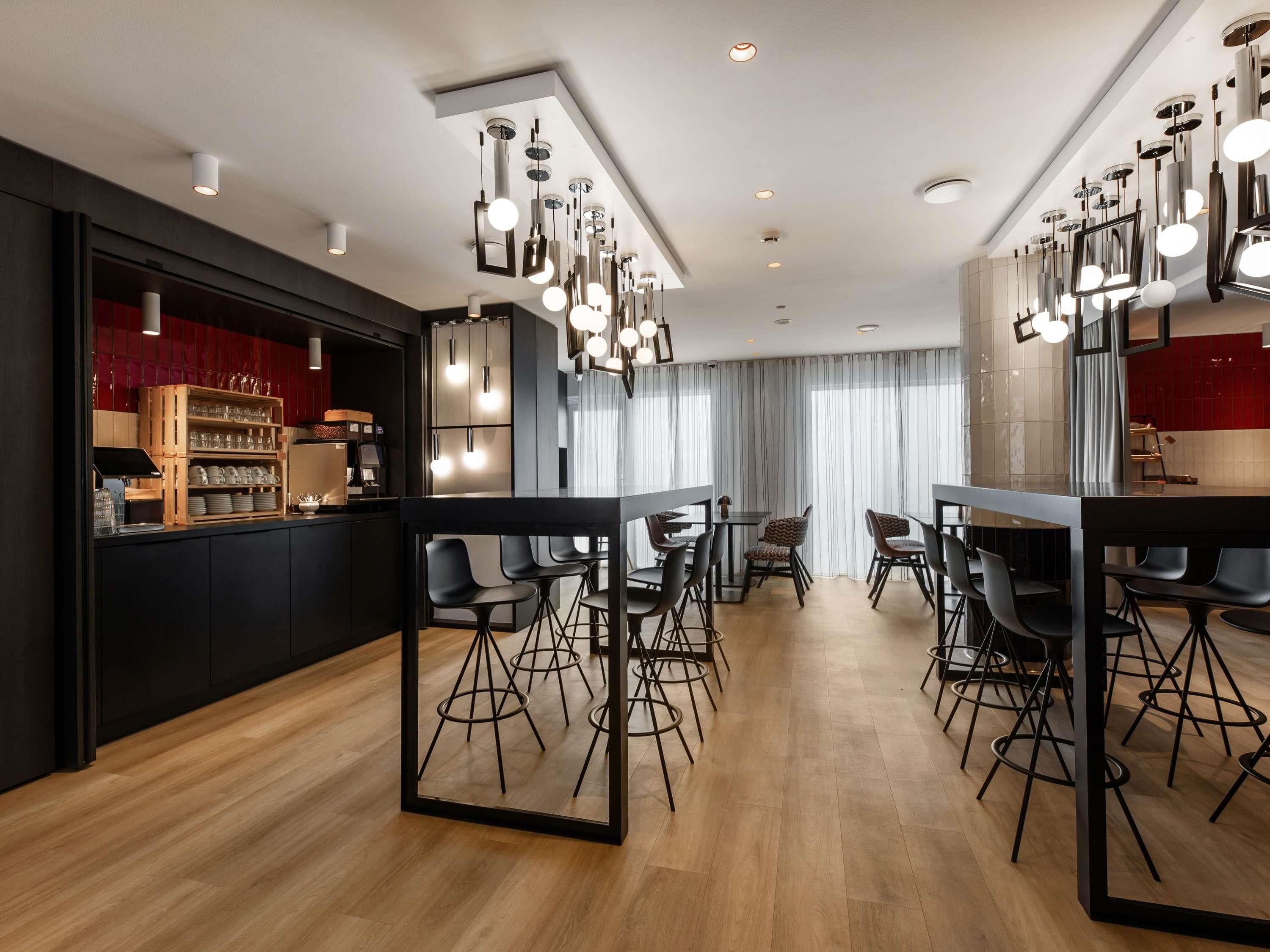 Ein moderner Essbereich mit Bar, schwarzen und weißen Stühlen und Pendelleuchten.