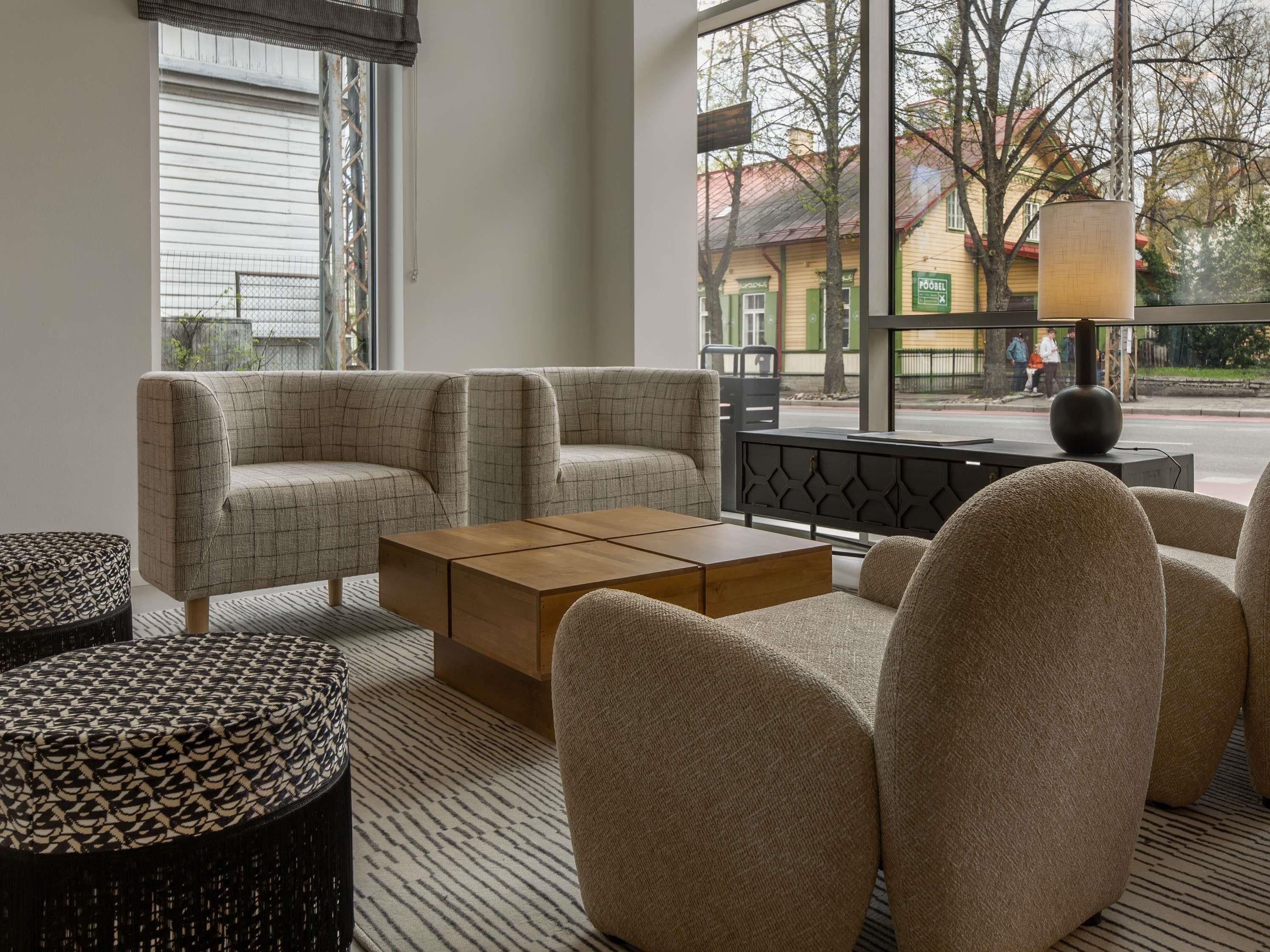 A modern living room with a sofa set, a wooden coffee table, and a patterned ottoman.