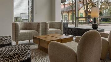 A modern living room with a sofa set, a wooden coffee table, and a patterned ottoman.