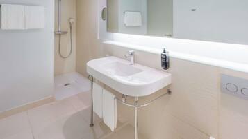 Un bagno moderno con un lavandino bianco, un ampio specchio e una doccia.